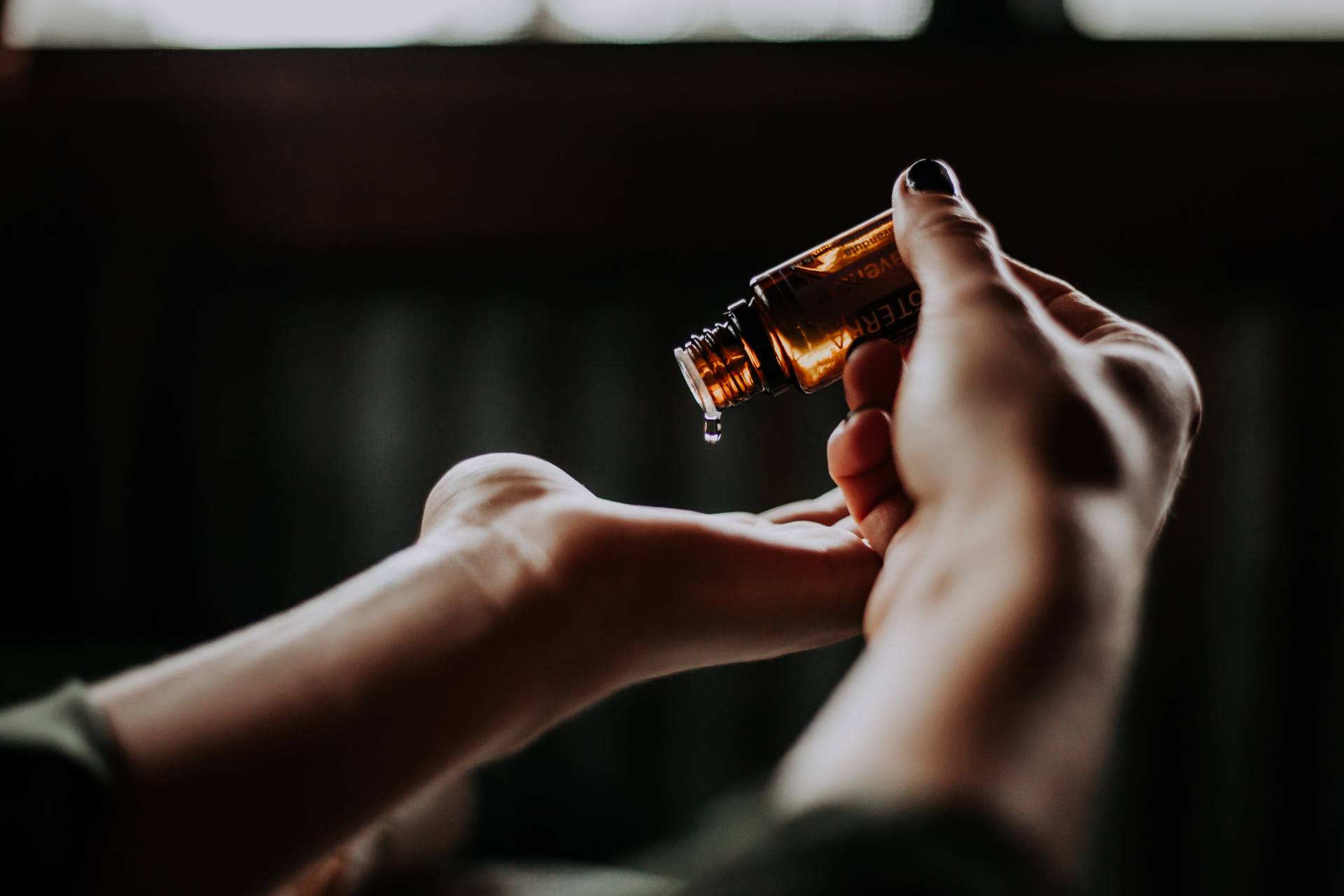 brown bottle of skincare being dispensed into hand