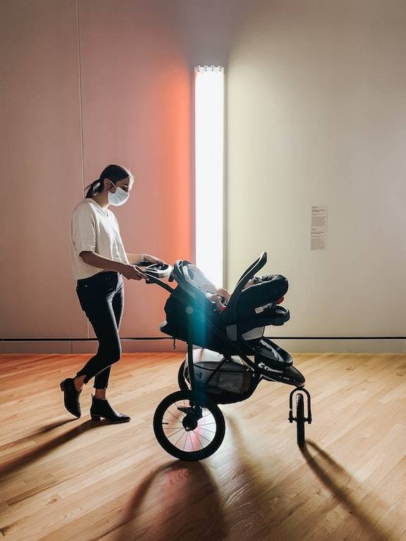 woman pushing a pram in a room with light walls and wood floors